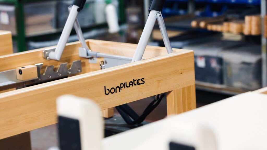 Detalle de madera noble con el logotipo de Bonpilates grabado en un Reformer de fabricación local.